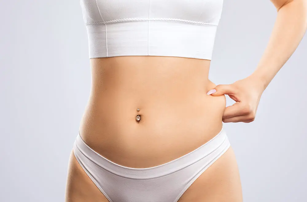 A woman in white underwear is pointing to her stomach.